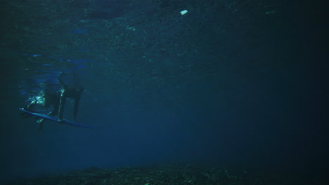 Panorámica-Hacia-Una-Persona-Que-Empuja-Una-Tabla-Bajo-El-Agua-Mientras-Un-Pato-Se-Zambulle-Mientras-La-Poderosa-Energía-De-Las-Olas-Pasa-Sobre-Ella.