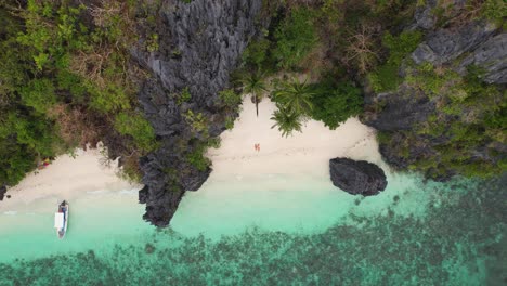 4K-drone-video-of-a-couple-laying-on-Entalula-Island-in-Palawan,-Philippines