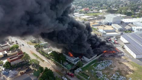 Building-burning-out-of-control-with-thick-black-smoke,-air-pollution,-aerial