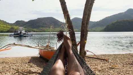 POV-video-taken-from-a-woman's-perspective-as-she-relaxes-in-a-hammock-on-a-beautiful-morning-on-an-island-in-Palawan,-Philippines