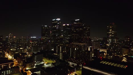 Eine-Bezaubernde-Luftaufnahme-Der-Innenstadt-Von-Los-Angeles-Bei-Nacht,-Mit-Den-Berühmten-Wolkenkratzern-Der-Stadt,-Die-Vor-Dem-Dunklen-Himmel-Beleuchtet-Sind