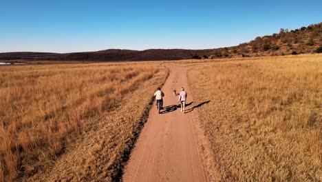 A-boy-riding-a-bicycle-with-his-Mom-and-playful-English-Springer-Spaniel-in-the-countryside,-on-an-isolated-dirt-road