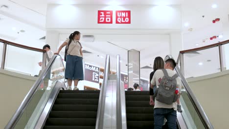 Los-Compradores-Viajan-En-Las-Escaleras-Mecánicas-Del-Centro-Comercial-Cuando-Llegan-A-La-Tienda-Uniqlo-De-La-Marca-De-Ropa-Japonesa-En-Hong-Kong