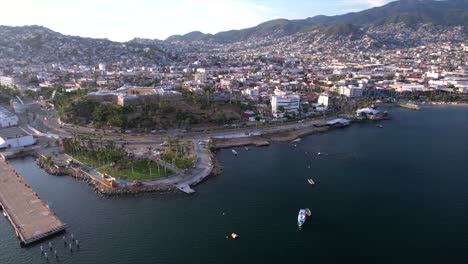 Dolly-out-drone-high-angle-shot-reveals-Acapulco-gulf-bay,-luxury-residential-area-and-ocean-coastline-in-Mexico