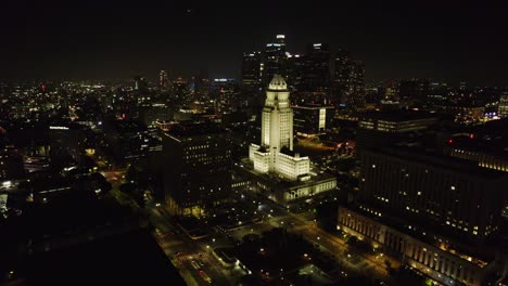 Experimente-La-Impresionante-Vista-Aérea-Nocturna-Del-Centro-De-Los-Ángeles,-Destacando-El-Ayuntamiento-Bellamente-Iluminado-Y-Las-Vibrantes-Luces-De-La-Ciudad.