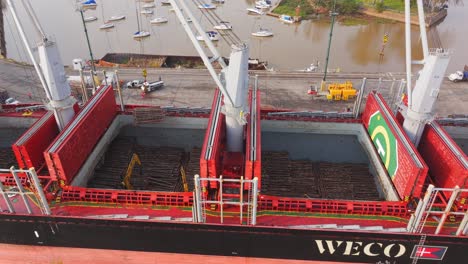 Cargo-ship-Weco-Laura-along-Uruguay-river-loading-logs-with-cranes-and-excavators