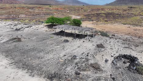 Aerial-View-of-Primitive-Sunshade-on-Abandoned-Beach-of-Volcanic-Island,-Cape-Verde