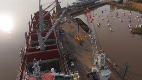 Cargo-ship-Weco-Laura-along-Uruguay-river-loading-logs-with-cranes-and-excavators