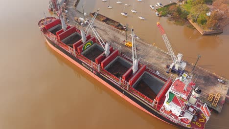 Cargo-ship-Weco-Laura-along-Uruguay-river-loading-logs-with-cranes-and-excavators