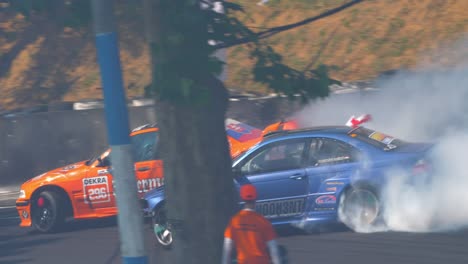 Orange-BMW-and-blue-BMW-race-cars-drifting-and-burning-tires-with-lots-of-smoke