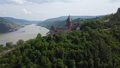 Castillo-Medieval-De-Stahleck-En-La-Cima-De-Una-Colina-Con-Vistas-Al-Valle-Del-Río-Rin,-Vista-De-Drones