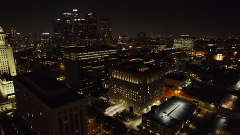 Witness-the-vibrant-cityscape-of-Downtown-Los-Angeles-at-night,-showcasing-illuminated-skyscrapers-and-bustling-city-streets-in-a-breathtaking-aerial-view