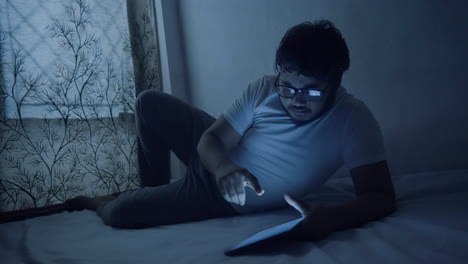 unhappy-man-watching-bad-news-on-digital-tablet-at-late-night-while-sleeping-on-bed