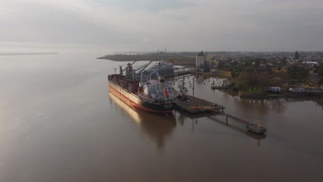 Cargo-ship-Weco-Laura-along-Uruguay-river-loading-logs-with-cranes-and-excavators