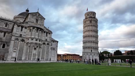 Visitors-walk-in-front-of-the-Leaning-Tower-of-Pisa-and-the-Cathedral-of-Pisa-in-Italy,-showcasing-the-unique-architectural-marvels-and-historical-significance-of-these-iconic-landmarks