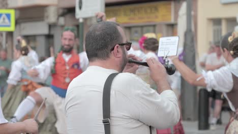 Músico-Tocando-Un-Instrumento-De-Viento,-Una-Chirimía-O-Dulzaina,-Un-Instrumento-Tradicional-Valenciano,-Durante-Un-Evento-Cultural,-Mientras-Los-Participantes-De-Las-Fallas-Bailan