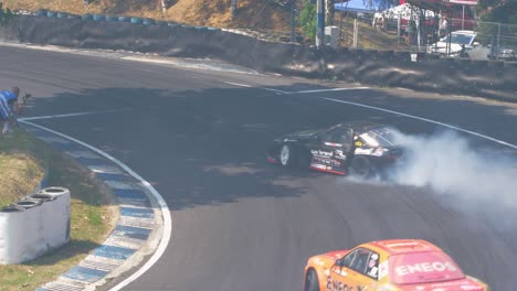 Two-race-cars-drifting-and-burning-tires-with-lots-of-smoke-on-a-very-tight-curve