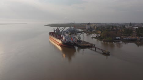 Cargo-ship-Weco-Laura-along-Uruguay-river-loading-logs-with-cranes-and-excavators