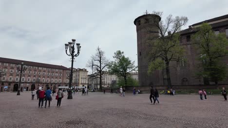 Gente-Caminando-Por-La-Plaza-En-Turín,-Italia,-Capturando-El-Ambiente-Animado-Y-El-Encanto-Cultural-De-Esta-Ciudad-Histórica.