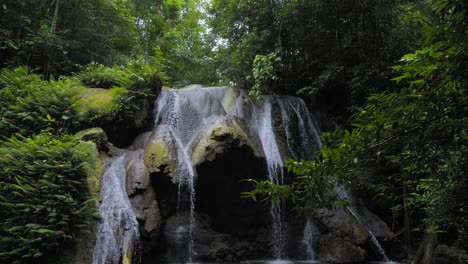 A-breathtaking-War-Inkabom-Waterfall-on-Batanta-Island-in-Raja-Ampat,-Indonesia,-cascades-down-a-rocky-cliff,-surrounded-by-lush-greenery