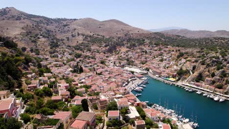 Aerial-footage-highlighting-the-colorful-houses-on-Symi-Island-in-Greece,-showcasing-vibrant-architecture