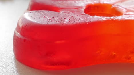 Very-close-diagonal-panning-movement-of-big-jelly-bear-and-mixed-unfocused-jellies-behind-on-white-table-in-studio-enviroment-at-home