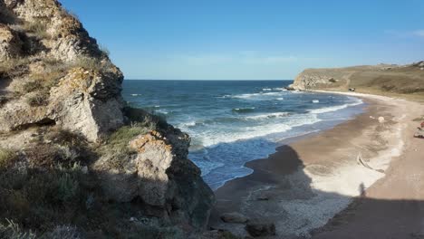 Waves-gently-crash-against-the-tranquil-shores-of-Crimea,-revealing-the-beauty-of-the-coastline-by-the-Sea-of-Azov-under-a-clear-blue-sky