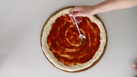 Preparing-Tomato-Sauce-On-A-Dough-Pizza-Base