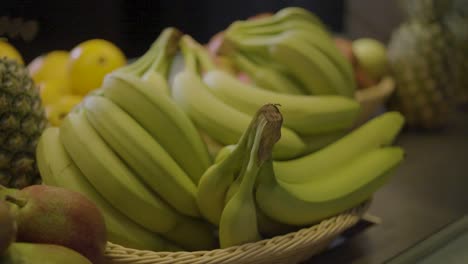 Una-Canasta-Llena-De-Plátanos-Frescos-En-Exhibición-Con-Otras-Frutas-En-El-Fondo.