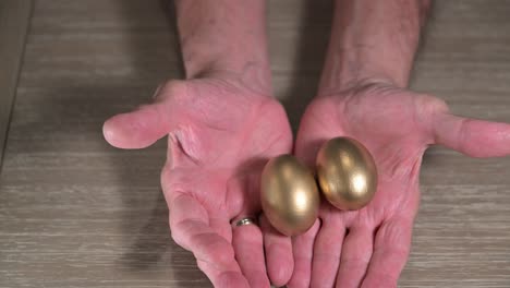 manly-elderly-male-hands-move-forward-to-show-two-golden-eggs-for-his-retirement-savings