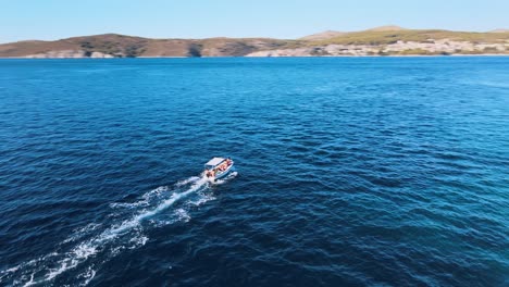 Aerial-drone-shot-of-a-small-boat-cruising-on-a-blue-seawater-near-the-coast-of-Hvar-island