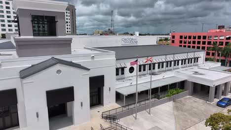 Aerial-establishing-shot-of-Caloosa-Sound-Convention-Center-in-Fort-Myers-with-waving-american-and-Florida-flag