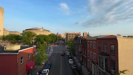 Drone-flyover-american-city-during-golden-hour-with-parking-cars-on-street