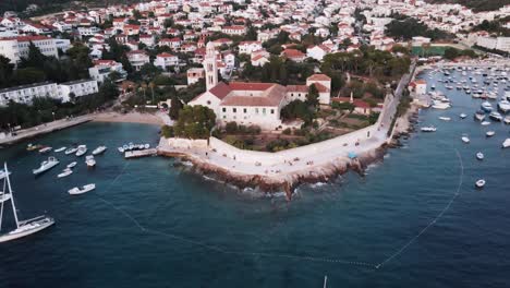 Aerial-drone-shot-of-an-old-town-of-Hvar-with-a-church-and-boats-in-the-background