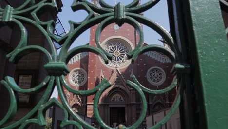 Observando-A-Través-De-Una-Valla-Metálica,-La-Iglesia-Católica-Romana-De-Santa