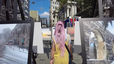 Happy-beautiful-woman-tourist-in-fashionable-summer-dress-walking-through-the-rows-of-painted-canvas-on-the-street-of-Istanbul