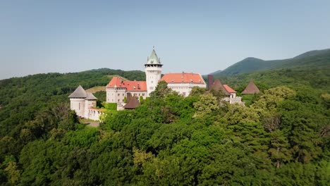 Aerial-view-of-Smolenice-Castle-in-Slovakia,-surrounded-by-lush-forested-hills