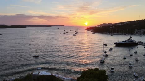 A-drone-flies-backward-at-sunset-on-the-coast-of-Hvar-town-in-Croatia-while-a-church-tower-appears-in-the-foreground