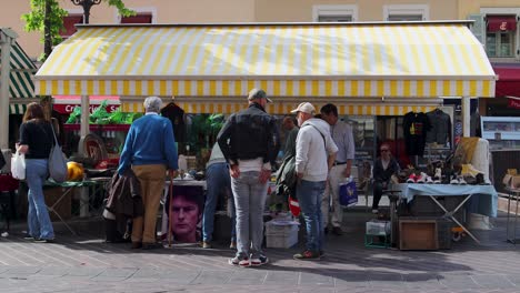 Menschen-Stöbern-An-Einem-Antiquitätenmarktstand-Auf-Dem-Cours-Saleya-In-Nizza,-Frankreich-Unter-Einem-Gestreiften-Baldachin