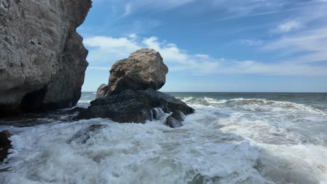 Waves-roll-in-powerfully,-splashing-against-the-rocky-coastline-of-Crimea,-showcasing-the-beauty-of-the-Sea-of-Azov-on-a-clear-day