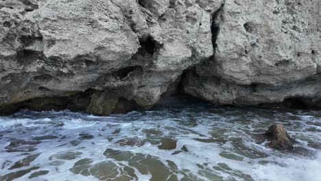 Waves-crash-against-rugged-cliffs,-highlighting-the-stunning-rock-formations-along-Crimea’s-coastline-by-the-Sea-of-Azov-during-sunset