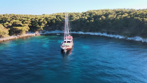 Aerial-drone-shot-of-an-old-pirate-sailing-boat-waiting-on-the-blue-sea-near-the-coast