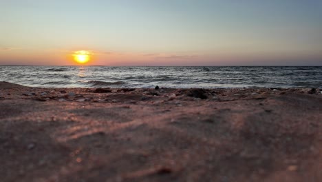 The-sun-sets-beautifully-over-the-calm-waters-of-the-Sea-of-Azov,-casting-warm-hues-across-the-sky-and-creating-a-serene-atmosphere-along-the-shoreline