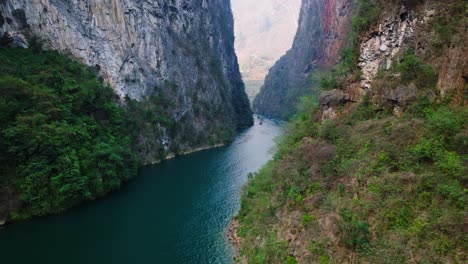 Este-Video-Con-Dron-Captura-La-Impresionante-Belleza-Del-Cañón-De-Ha-Giang-En-El-Norte-De-Vietnam,-Mostrando-Los-Imponentes-Acantilados-Y-Las-Tranquilas-Aguas-Azules-Con-Barcos-Navegando-Pacíficamente-Por-El-Cañón.