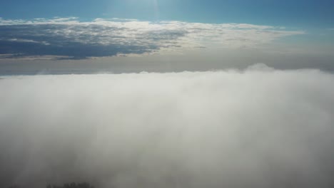 Aerial-descend-through-dense-morning-fog-over-land,-Latvian-countryside