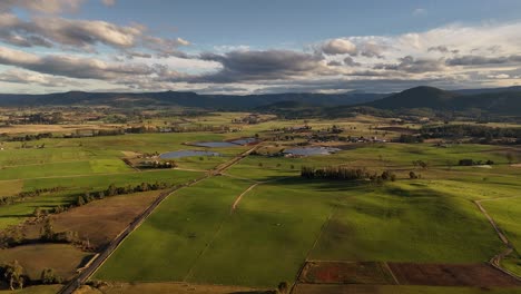 Magnífico-Paisaje-De-Tasmania-Con-Campos-Montañosos,-Lago-Y-Montañas-Durante-La-Puesta-De-Sol-Dorada