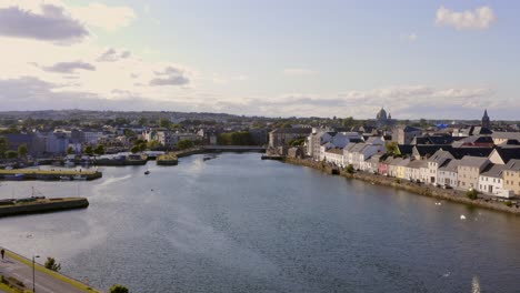 Aerial-pullback-showcasing-the-River-Corrib,-Galway’s-iconic-Long-Walk,-and-Claddagh-on-a-sunny-day