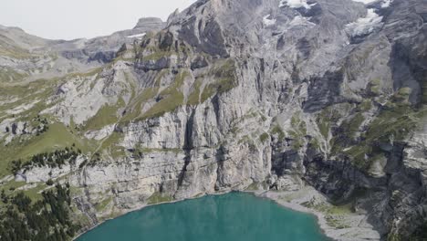 Clear-turquoise-lake-surrounded-by-rocky-cliffs-in-Oeschinensee,-Switzerland