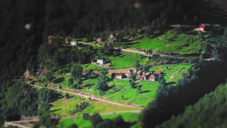 Una-Vista-Aérea-De-Un-Pintoresco-Pueblo-De-Montaña-Con-Exuberantes-Campos-Verdes-Y-Casas-Dispersas.