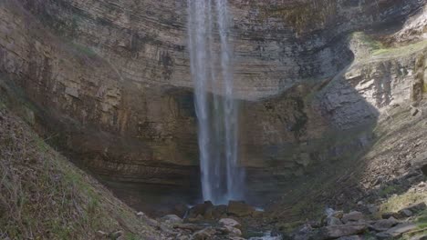 Majestic-waterfall-cascades-down-rocky-cliff-into-serene-pool-below-in-natural-setting